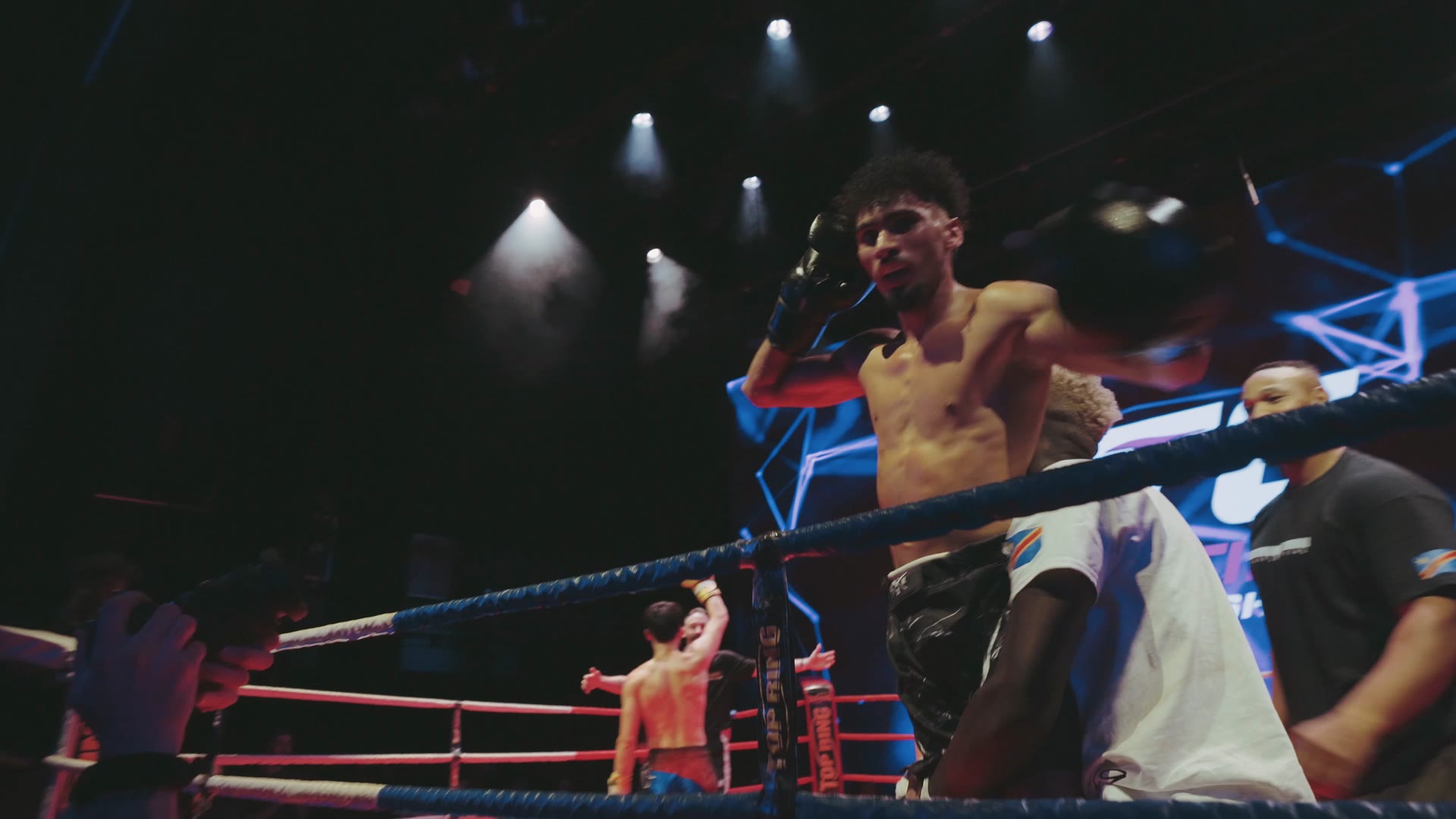 Combattant dans le coin du ring sous les lumières et l'écran FTC